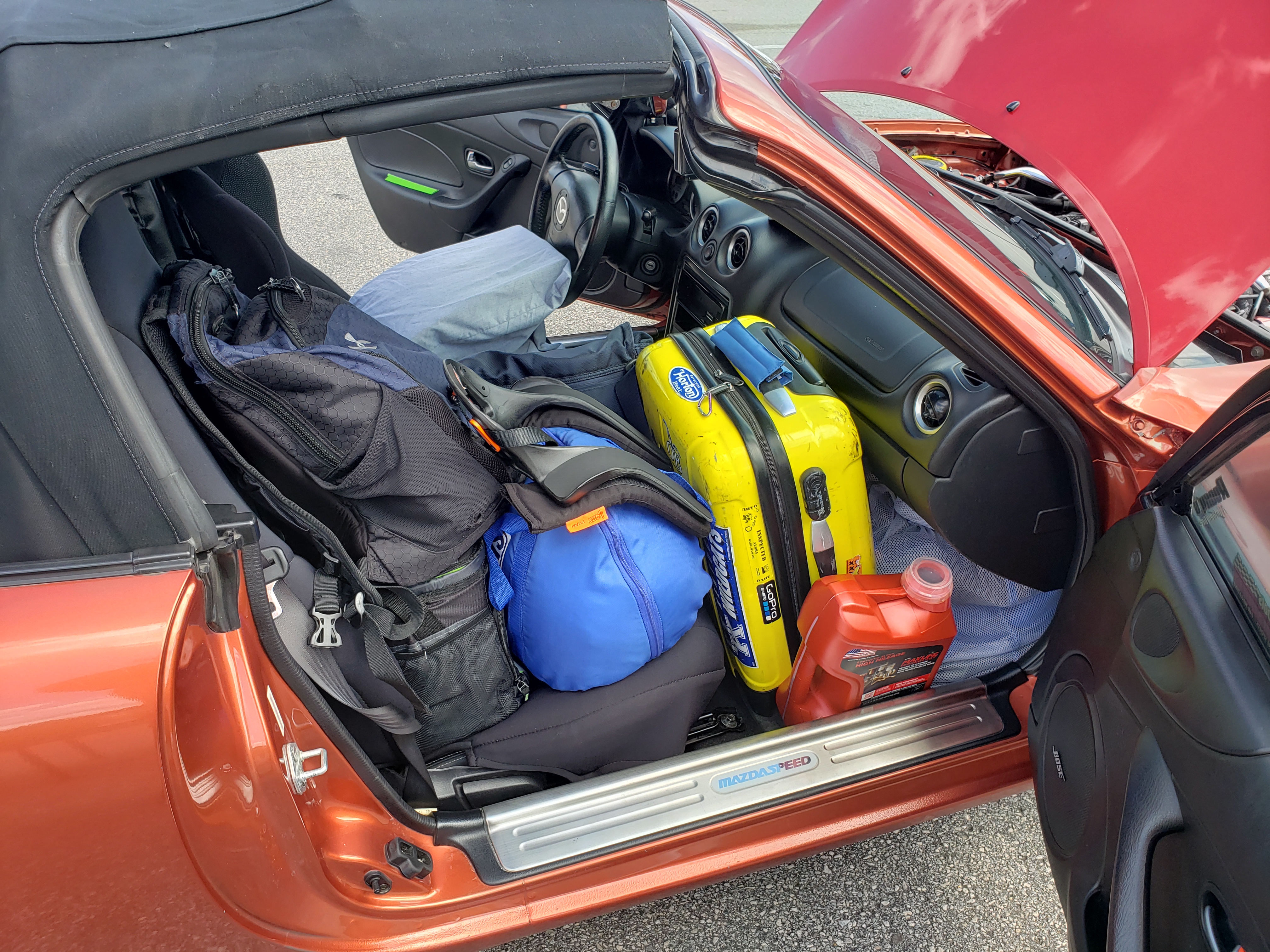 Full passenger seat. Blue bag for helmet. Yellow suitcase (carry-on size). Cooler, backpack, extra oil, and other items.